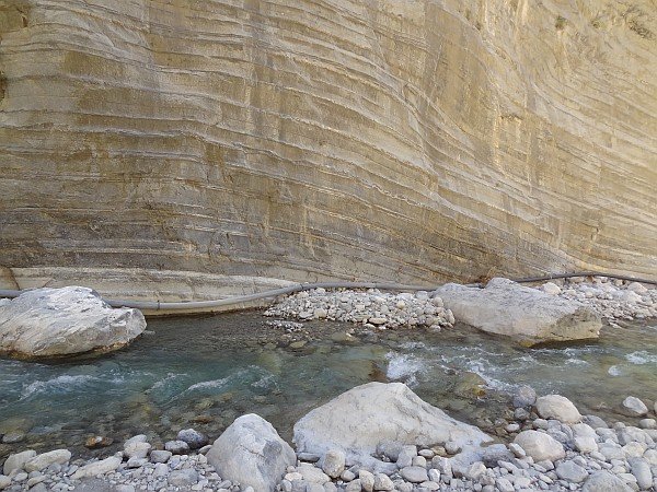 River flowing along striated cliff wall