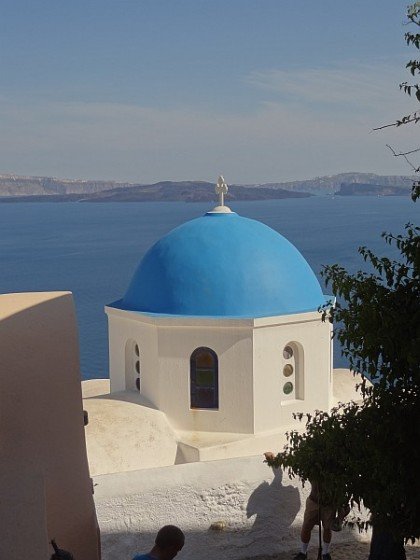 Blue domed church with caldera islands in background