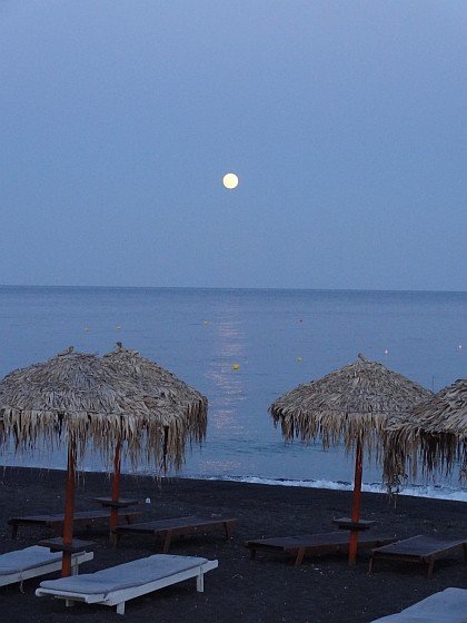 Rising moon between beach umbrellas